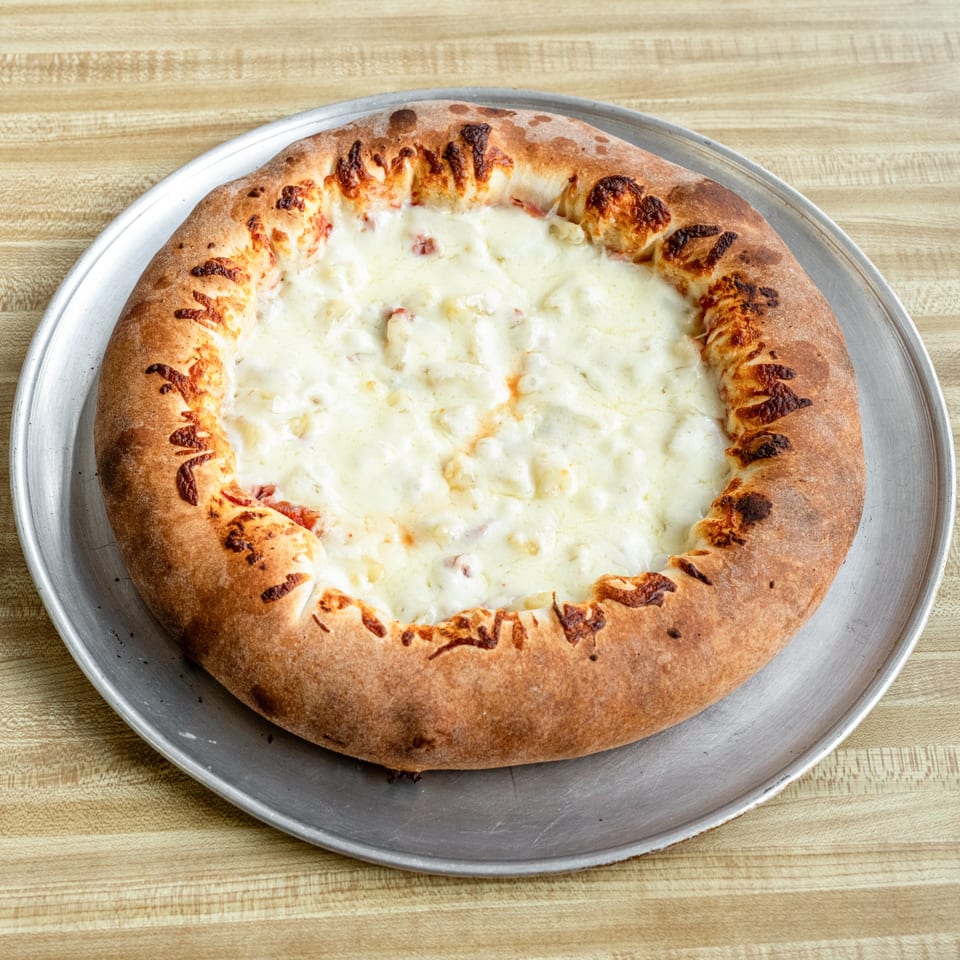 Raydee Magoo's white pizza with a thick, golden-brown crust on a metal pan.