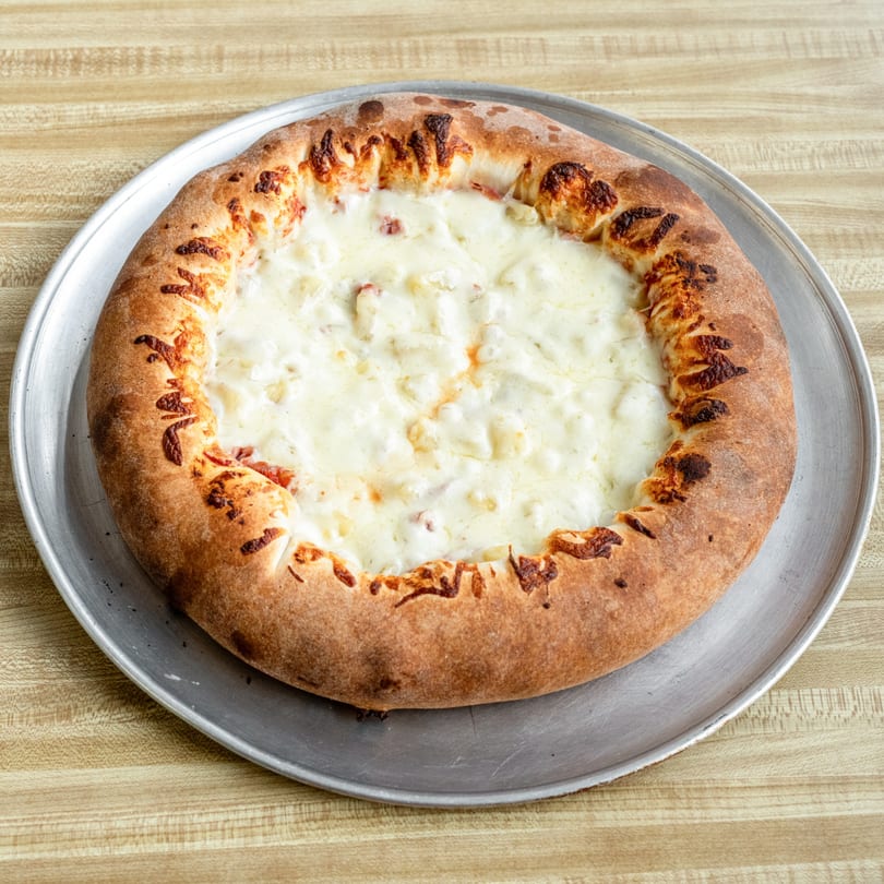 Raydee Magoo's white pizza with a thick, golden-brown crust on a metal pan.