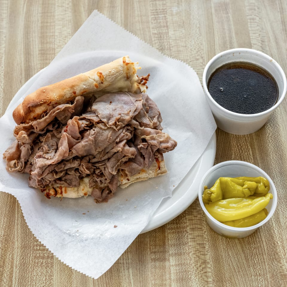 Raydee Magoo's Italian beef sandwich with a side of peppers and a drink.